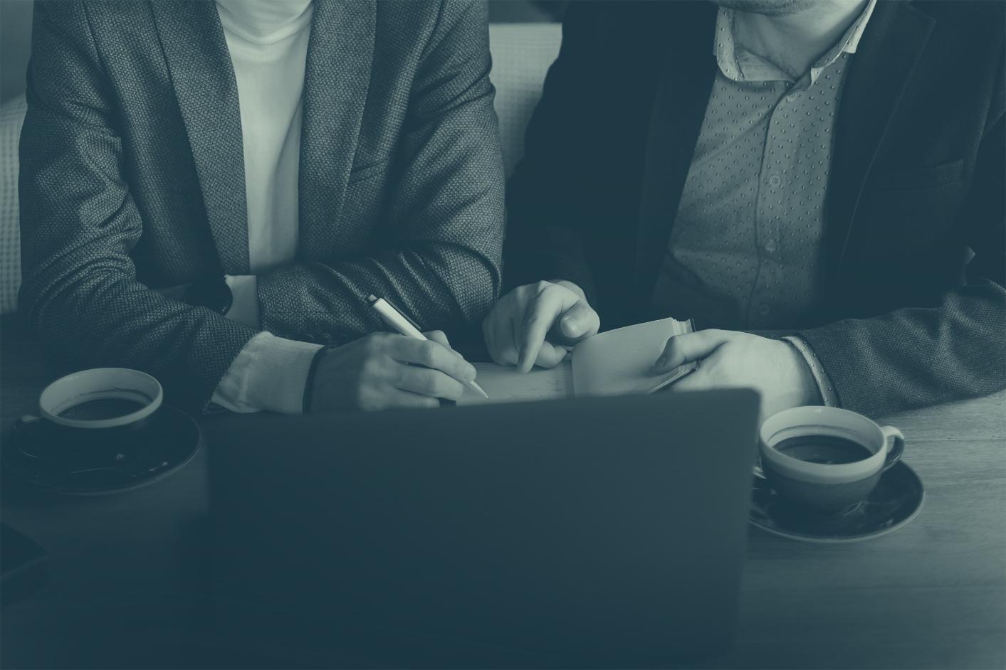Beratungsgespräch am Schreibtisch mit Unterlagen und Kaffee